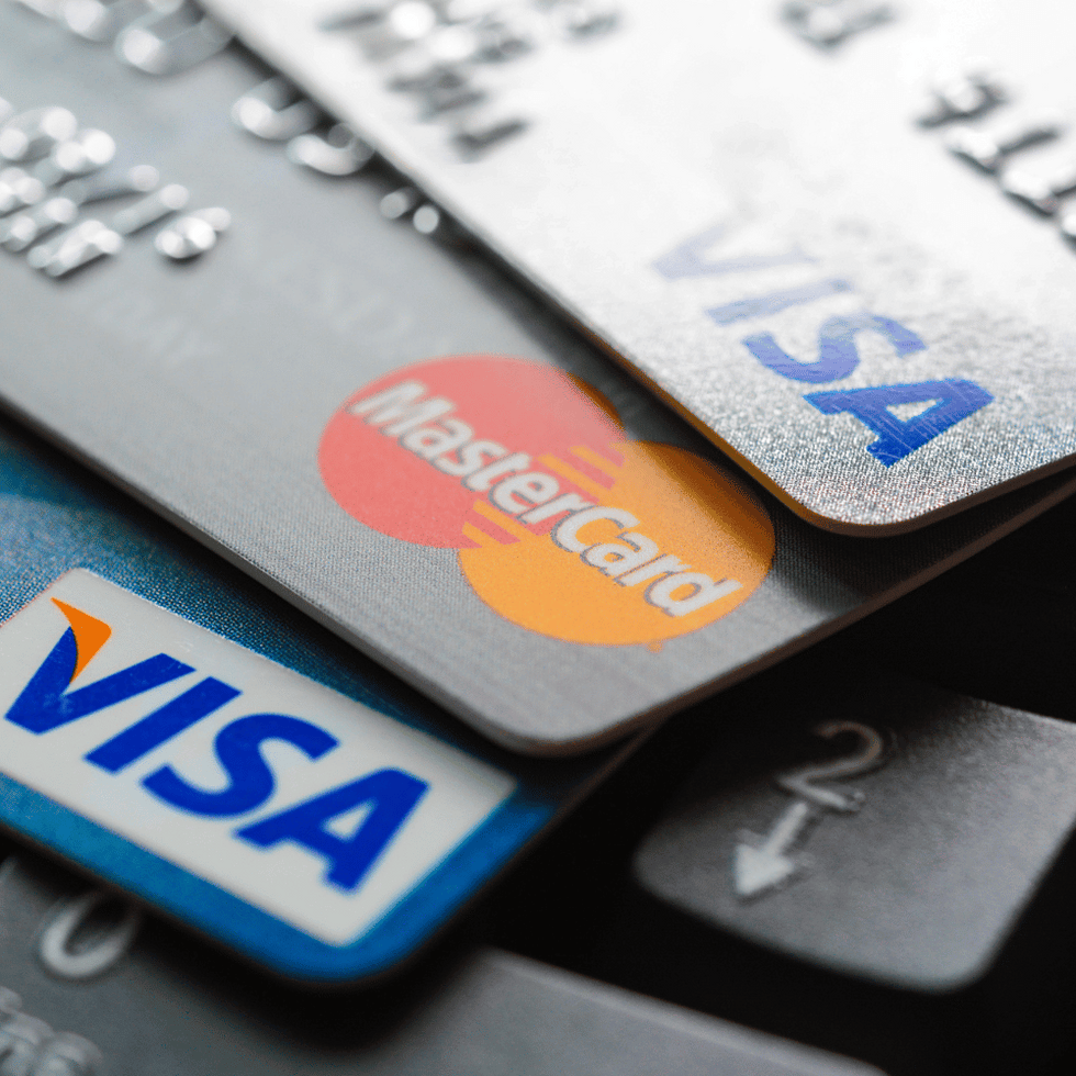 Close-up of stacked credit cards, featuring Visa and Mastercard logos, resting on a computer keyboard.