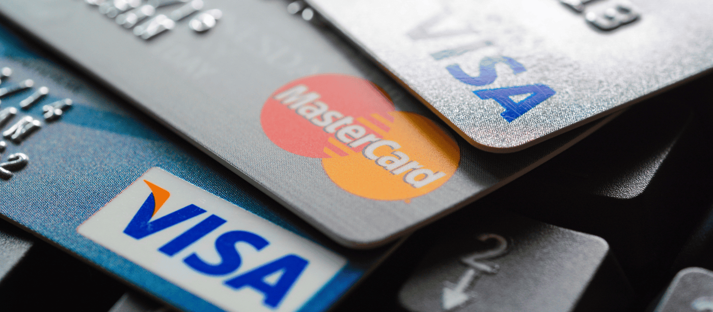 Close-up of stacked credit cards, featuring Visa and Mastercard logos, resting on a computer keyboard.